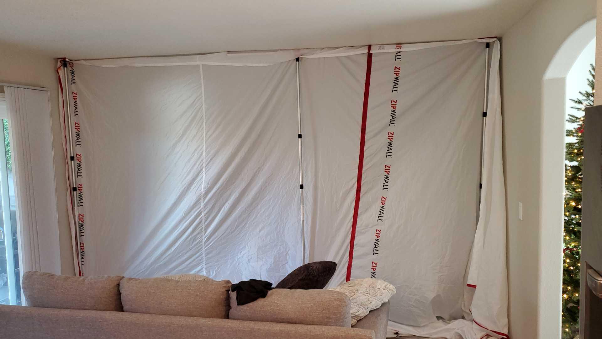 Plastic containment set up in a living room during water damage mitigation