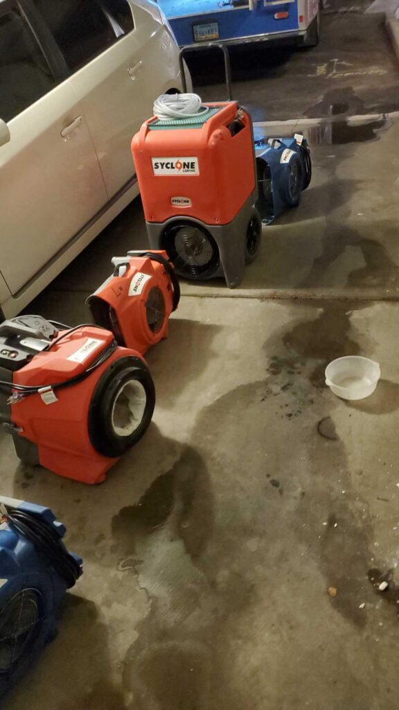 Dehumidifiers and air movers drying a garage floor