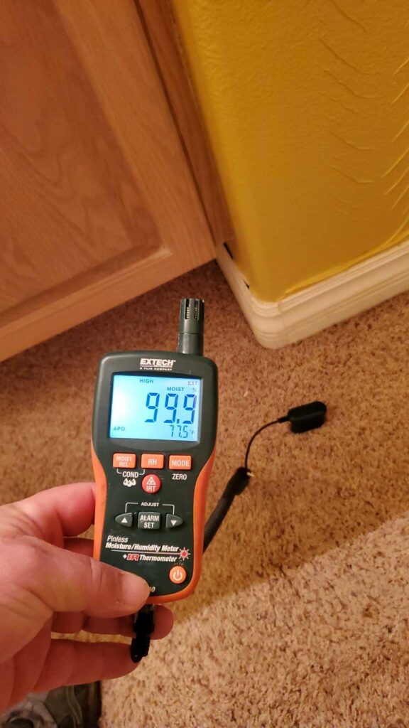 Moisture meter reading taken at the base of a kitchen cabinet